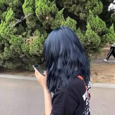 a woman with blue hair is looking at her cell phone