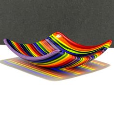 two colorful glass bowls sitting on top of a white table next to a black wall