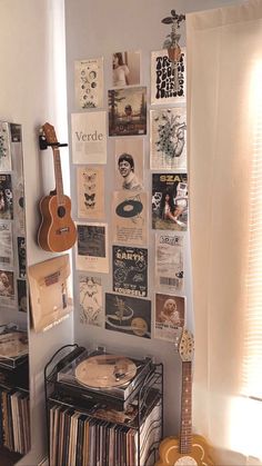 a room with a guitar, record player and various records on the wall next to it