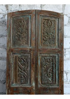 an old wooden door with intricate carvings on the doors and side panels, in front of a brick wall