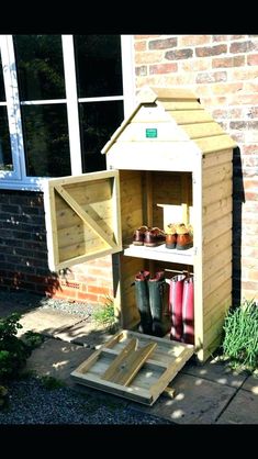 a potting shed is built into the side of a brick building and has rain boots in it