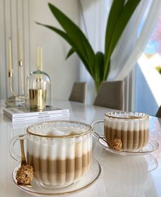 two coffee cups filled with liquid sitting on top of a table