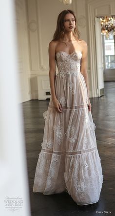 a woman in a white dress standing on a black floor next to a chandelier