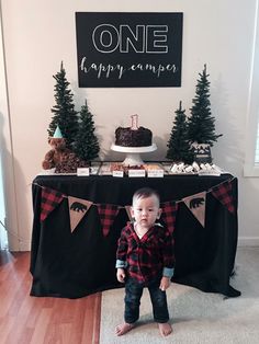 a young boy standing in front of a table with cake and decorations on top of it