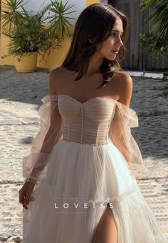 a woman in a white dress is standing on the beach