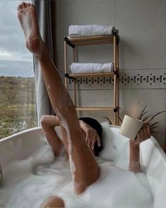 a woman laying in a bathtub with her feet up