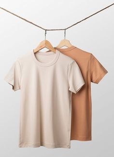 two t - shirts hanging on a clothes line, one is tan and the other is brown