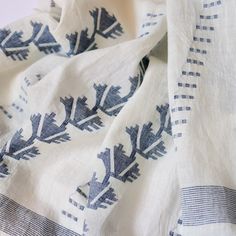 an embroidered white and blue cloth with leaves on it