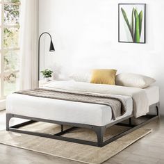 a white bed sitting in a bedroom on top of a hard wood floor next to a window