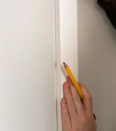 a person is holding a pencil in their left hand and pointing to the door handle