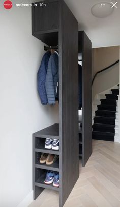 an open closet in the corner of a room with shoes and coats hanging on it