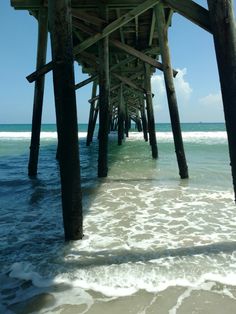 the underside of a pier with waves coming in