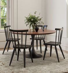 a dining room table with four chairs and a potted plant