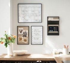 a wooden table topped with a vase filled with flowers next to pictures on the wall