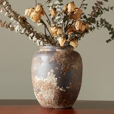 a vase filled with lots of flowers on top of a wooden table next to a wall