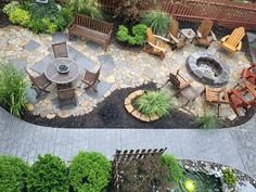 an aerial view of a patio with fire pit and seating area in the middle, surrounded by greenery