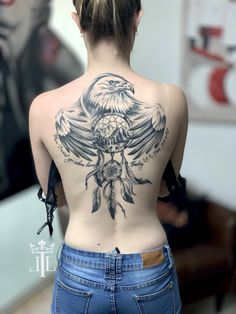 the back of a woman's body with an eagle and dream catcher tattoo on it