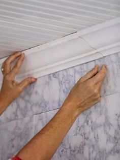 a person is working on a wall with white marble