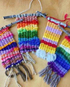 three knitted items are sitting on a wooden table, one is multicolored and the other has scissors