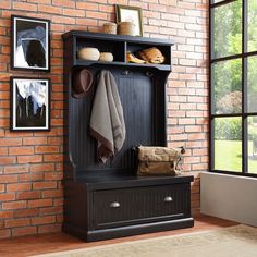 a wooden bench with a coat rack and hat on it in front of a brick wall