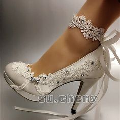 a woman's white high heeled shoes with lace and pearls on the ankle