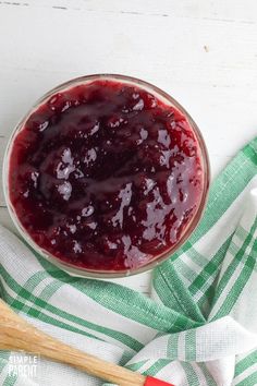 a glass bowl filled with cranberry sauce on top of a green and white towel