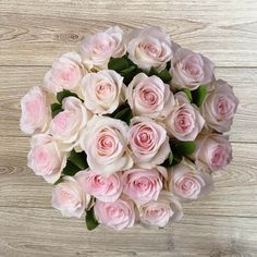 a bouquet of pink roses sitting on top of a wooden table