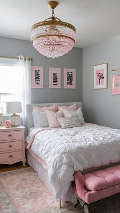 a pink and white bedroom with chandelier, bed, dressers and pictures on the wall