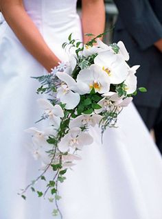 a bride and groom standing next to each other in front of a building with white flowers