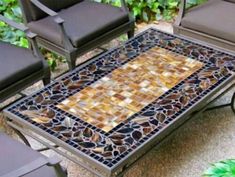 an outdoor table with chairs around it and a mosaic tile design on the top, surrounded by greenery