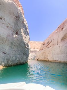 there is a boat that is in the water near some rocks and sand cliffs,