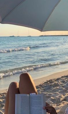 a woman reading a book on the beach