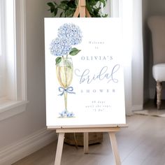 a blue hydrangea flower in a vase is on an easel next to a sign that says, ollivia's bridal shower