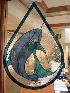 a stained glass window with a dolphin in the center and water droplets on it's side