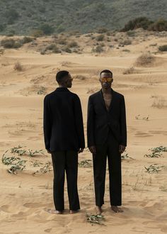 two men standing in the middle of a desert