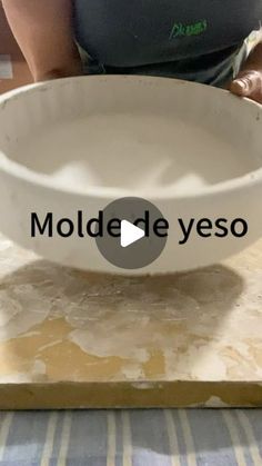 a white bowl sitting on top of a table next to a woman's hand