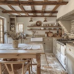 an old fashioned kitchen with white appliances and wood beams on the ceiling, along with stone flooring