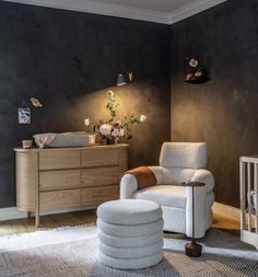 a baby's room with a chair, crib and dresser in it that has flowers on the wall