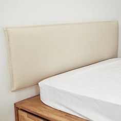 a bed with white sheets and wooden drawers