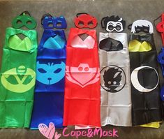 several different types of masks and capes are lined up in a row on the floor