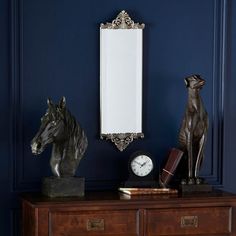 a horse statue sitting on top of a wooden dresser next to a mirror and clock