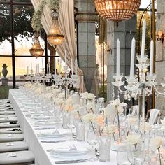 a long table is set up with white flowers and candles for an elegant wedding reception