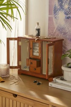 a small wooden cabinet sitting on top of a table next to a potted plant