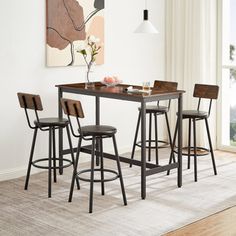 a dining table with four stools and a painting on the wall in the background