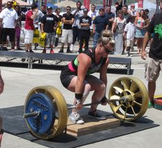 a woman squatting down on a bench with a barbell in front of her