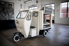 a small motor scooter is parked in an empty room with large windows on the wall