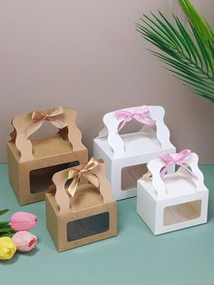 three small boxes with bows on them sitting next to tulips