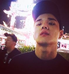 a young man standing in front of a building with lights on it's side