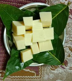 cubes of butter sit in a metal bowl on a leafy tablecloth with leaves