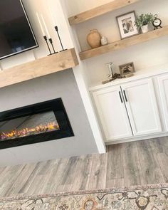 a fireplace in a living room with white cabinets and an area rug on the floor